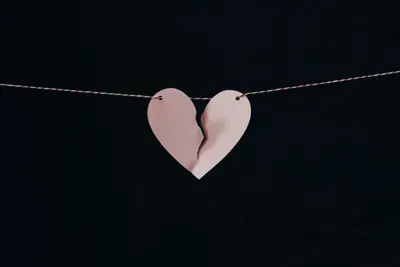 S paper heart cut out that is ripped down the middle pinned to a string.