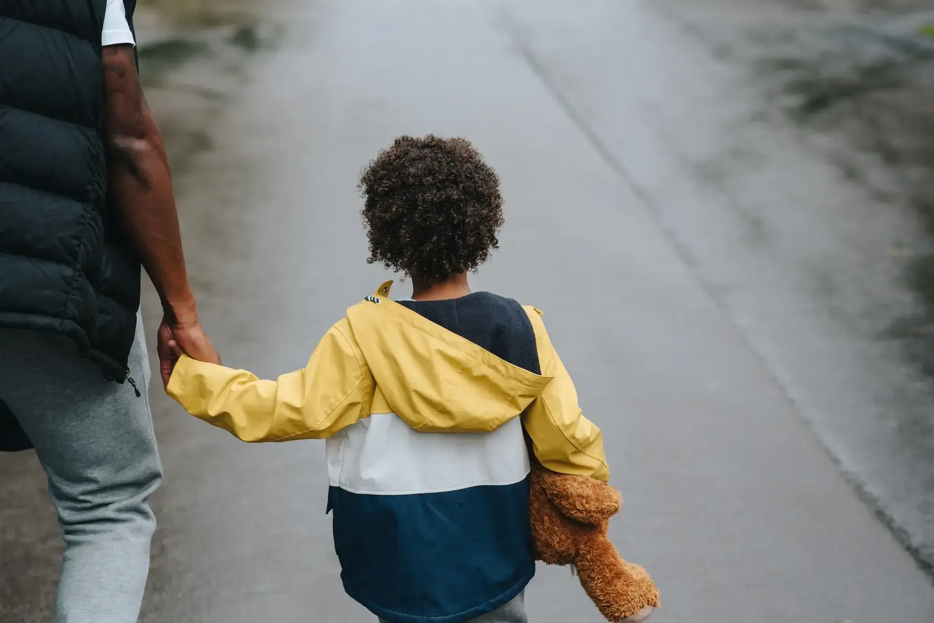 child and parent holding hands while walking